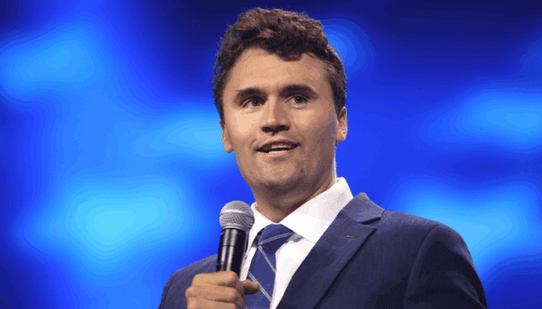 Charlie Kirk, de microfone na mão, fala numa conferência