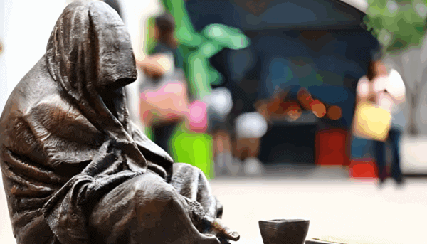 estátua de homem sentado no chão, a mendigar cabeça coberta, que olhado com atenção, se pode reconhecer como Jesus Cristo pelas chagas nas suas mãos