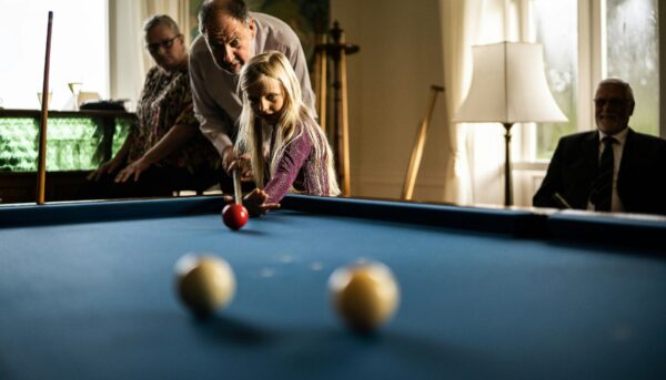 Avô ajuda a neta a segurar o taco num jogo de snooker.