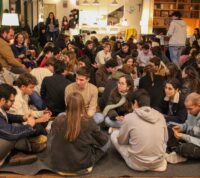 vários grupos de jovens sentando no chão de uma sala