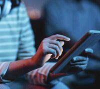 imagem parcial de alguém a usar um tablet num ambiente social e escuro