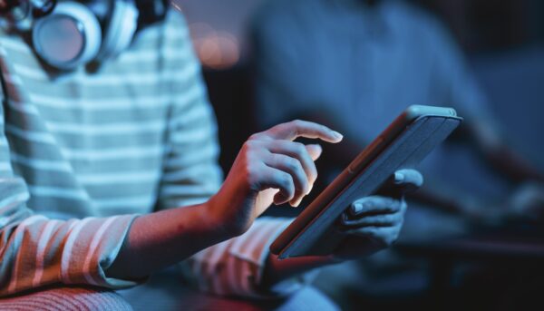 imagem parcial de alguém a usar um tablet num ambiente social e escuro
