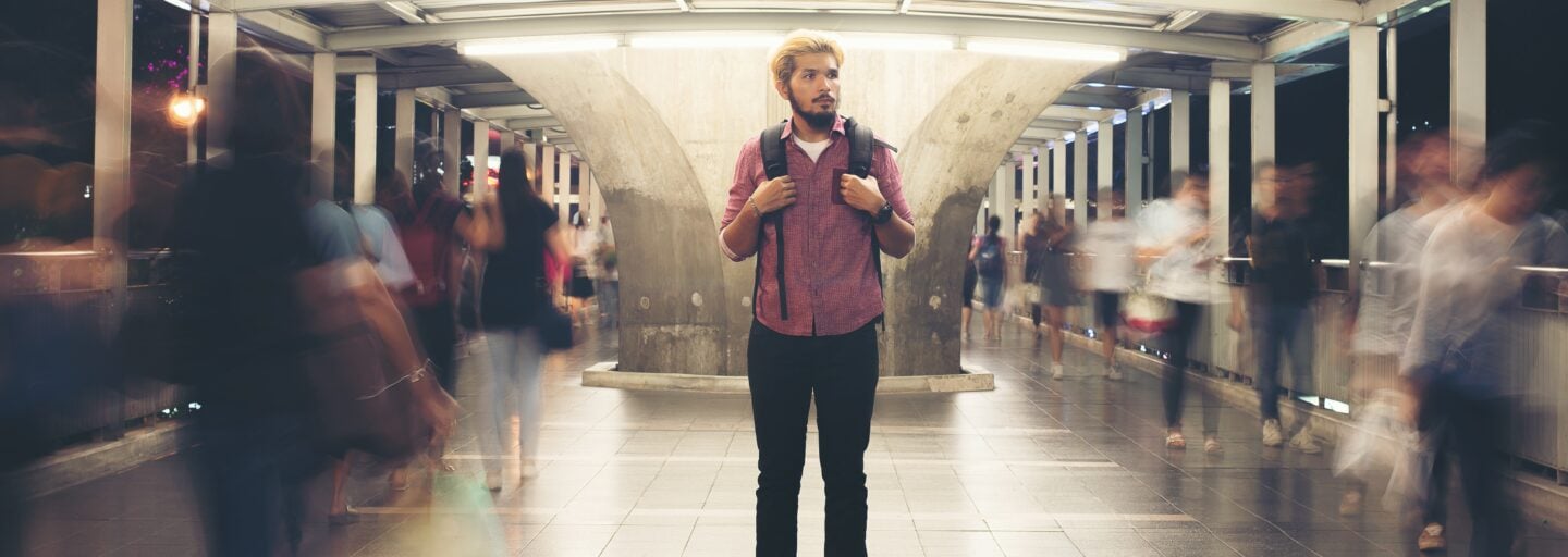 Handsome bearded man with backpack standing on the street traveling at night.