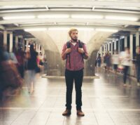 Handsome bearded man with backpack standing on the street traveling at night.