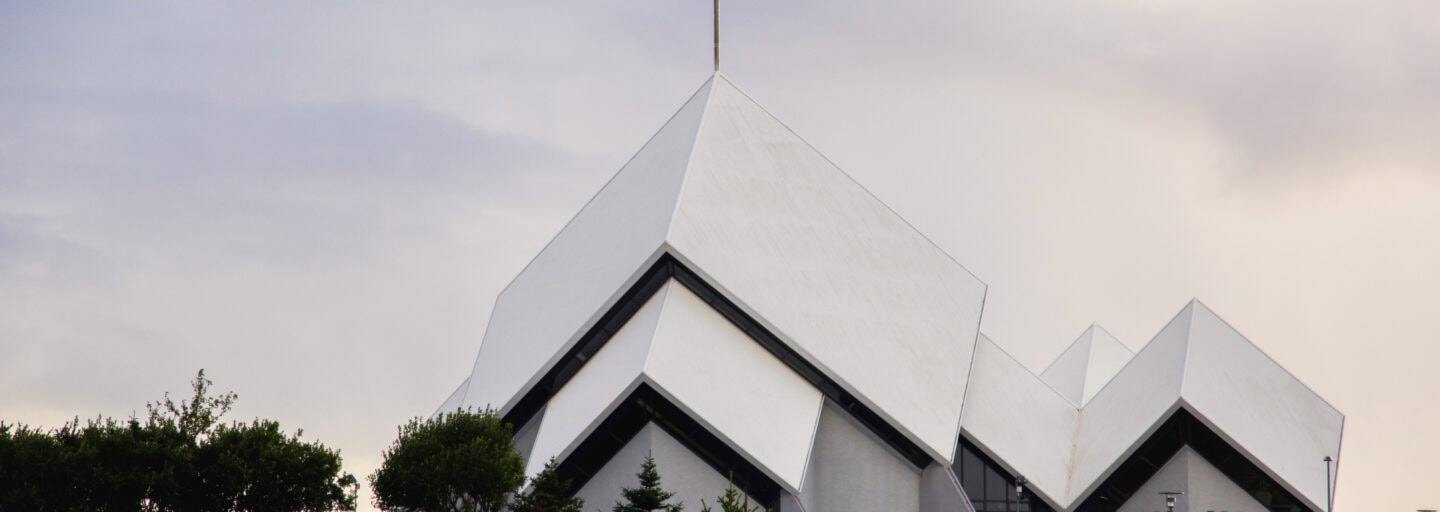 igreja moderna, branca, de telhados em planos inclinados simétricos como livro aberto pousado sobre uma mesa, num horizonte ao pôr do sol