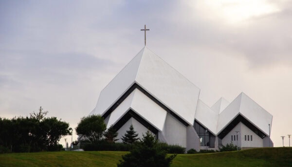 igreja moderna, branca, de telhados em planos inclinados simétricos como livro aberto pousado sobre uma mesa, num horizonte ao pôr do sol