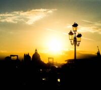 Bela paisagem urbana com silhuetas de um poste de iluminação e edifícios ao pôr do sol