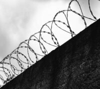 fotografia a preto e branco de muro coroado de serpentina de arame farpado