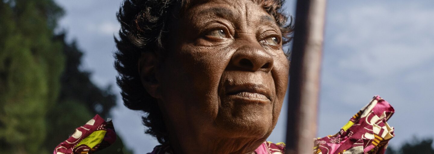 mulher negra olha com esperança para o horizonte, tendo a marca do passar dos anos marcada na cara