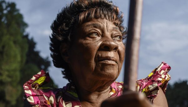 mulher negra olha com esperança para o horizonte, tendo a marca do passar dos anos marcada na cara