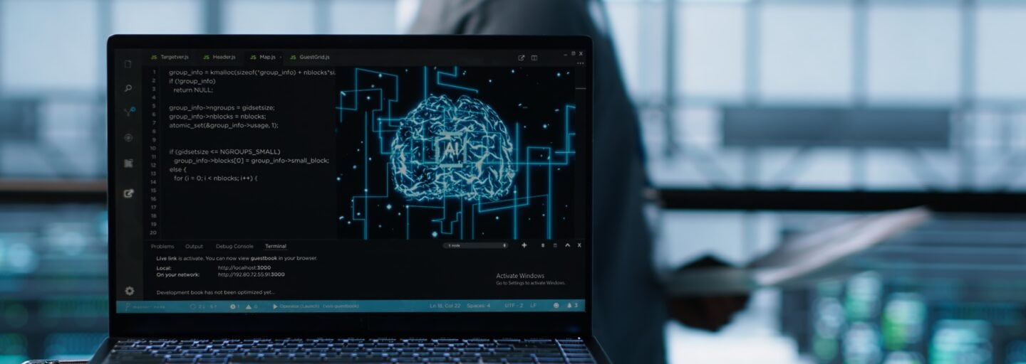 Tecnologia de inteligência artificial a programar num portátil num centro de dados, com programadores ao fundo a utilizar modelos de aprendizagem automática.