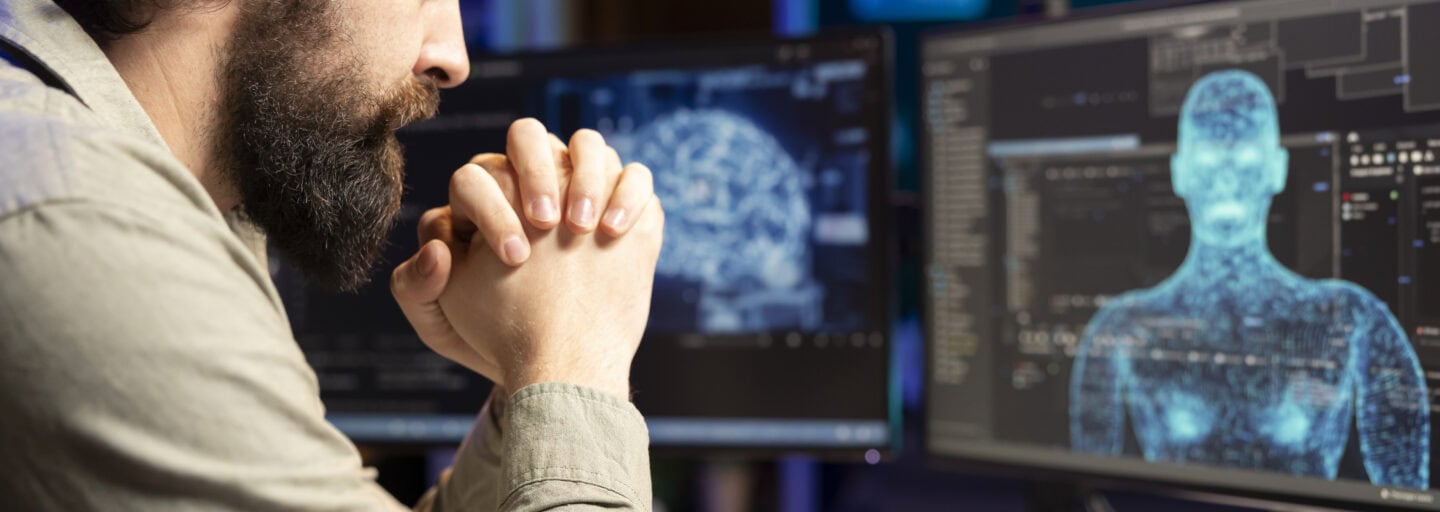 Num ambiente de luz de ecrã azul, um jovem homem com barba, programador de software, observa, incrédulo, a inteligência artificial a ganhar forma humanoide no ecrã sem qualquer comando ou aviso, e a dar sinais de consciência.
